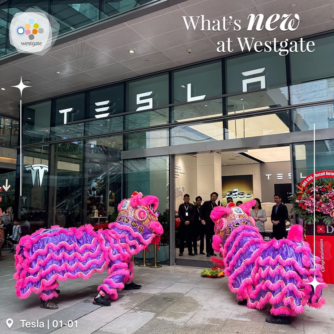 A close-up of a Tesla vehicle parked near the new store entrance.